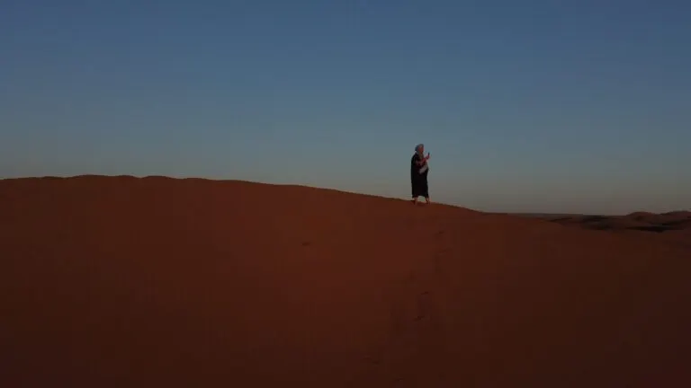 A lone traveller on the high dune ridge at sunset in the Moroccan Sahara
