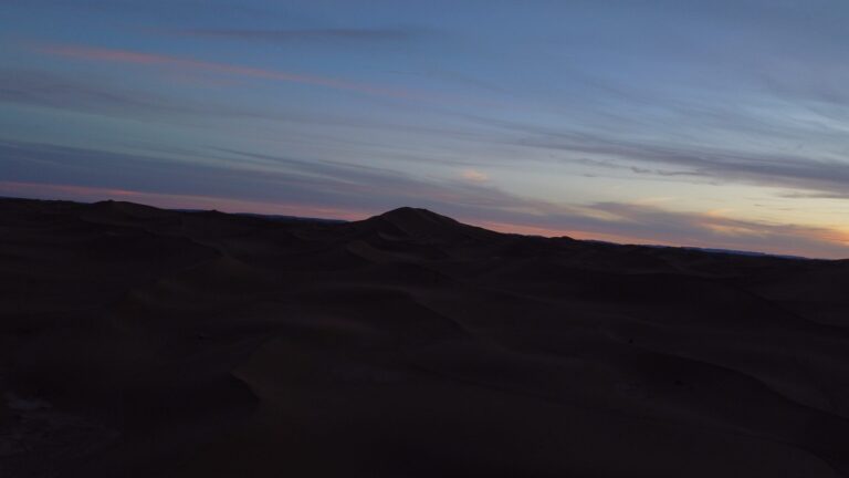 Desert camp seen from the air under a pastel evening sky