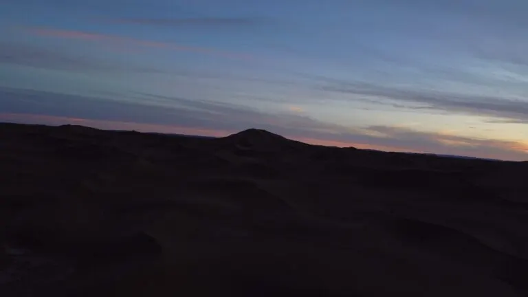 Desert camp seen from the air under a pastel evening sky