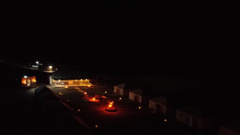The desert camp lit with warm lanterns after dark