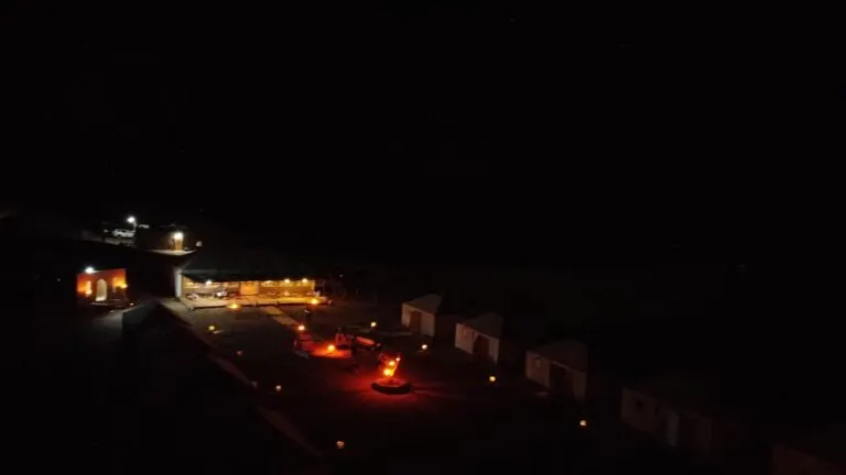The desert camp lit with warm lanterns after dark