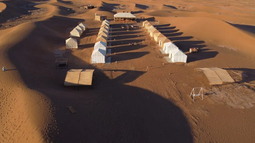 Rows of white desert tents casting long shadows across the Erg Chebbi dunes