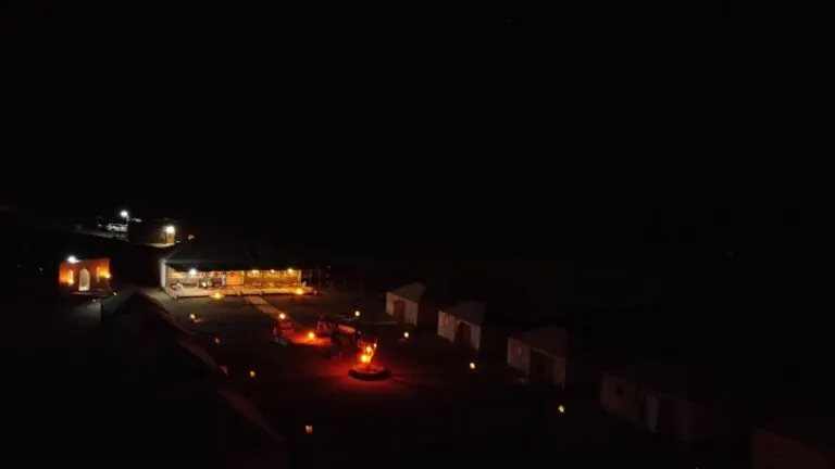 The desert camp lit up after dark beneath a dark sky