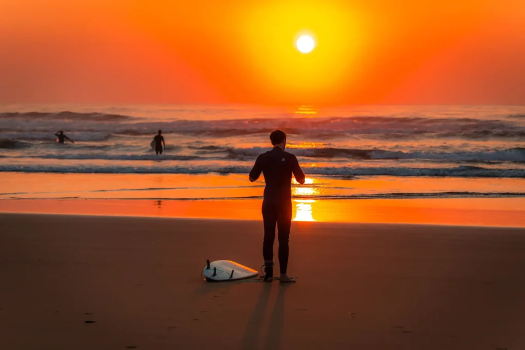Surfer preparing to enter the Atlantic at sunset in Morocco
