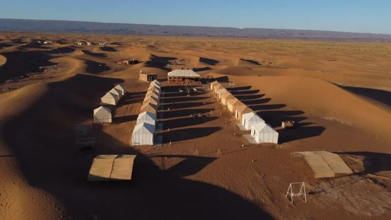 Luxury desert camp tents arranged among the Erg Chebbi dunes near Merzouga at golden hour