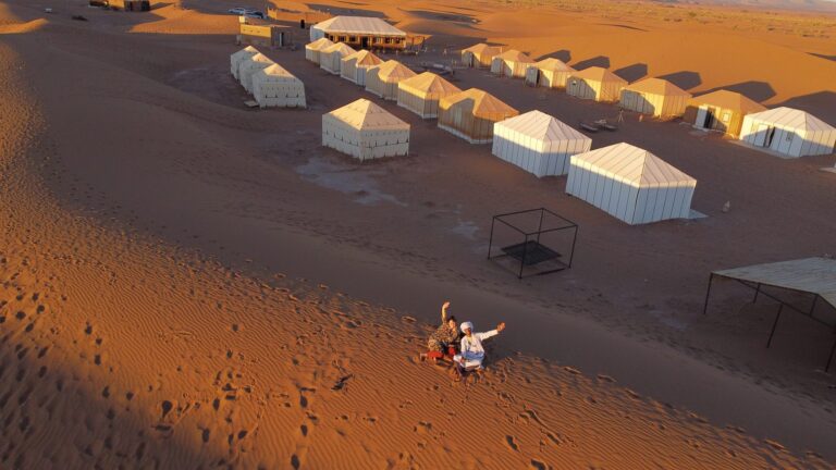 Travellers relaxing on the dune slope beside a Sahara desert camp